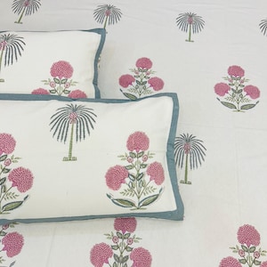 May include: White bedding set with a floral and palm tree pattern in pink, green, and gray. The set includes pillowcases with a teal border. The overall design is a repeating pattern of stylized flowers and palm trees.
