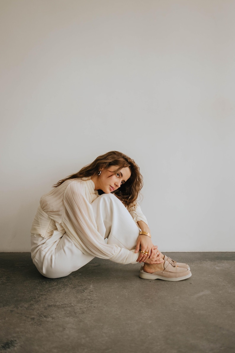 Classic beige suede backless loafers showing tassel detail and TPR sole