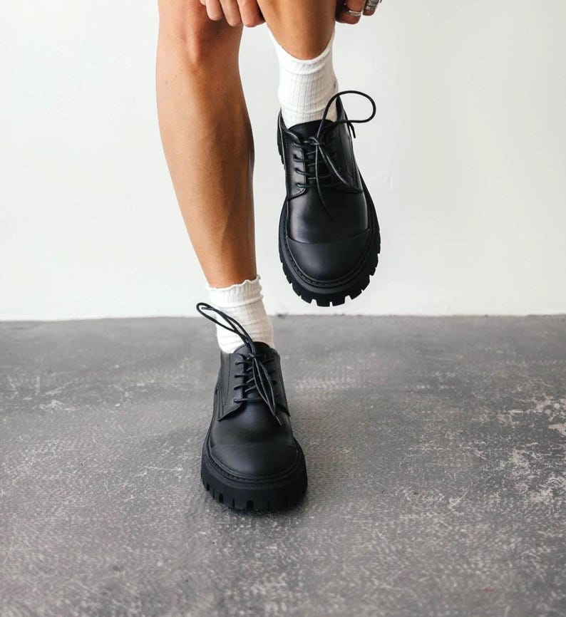 Black leather chunky sole loafers with lace-up design on white background