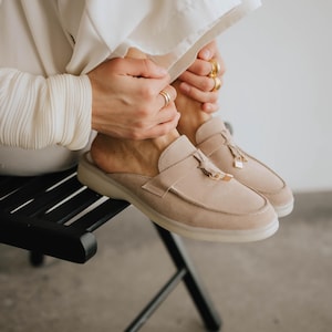 Elegant suede mule loafers in light beige with tassels, side angle view