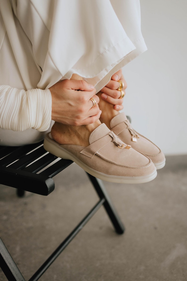 Elegant suede mule loafers in light beige with tassels, side angle view