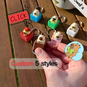 Peut inclure: Plusieurs porte-clés personnalisés avec de petites figurines d'animaux dans des boîtes carrées colorées. Les porte-clés sont de différentes couleurs, dont le rouge, le bleu, le vert, le rose et le blanc. L'image contient le texte "CLICK" et "Custom 5 styles".