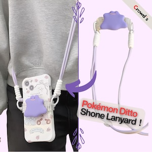 Peut inclure: Une lanière de téléphone violet clair représentant le personnage Ditto, dotée d'un cordon blanc et d'une attache en plastique transparent. Elle est fixée à une coque de téléphone blanche à motifs floraux avec le texte Best friend et l'étiquette Pokémon Ditto Shone Lanyard.