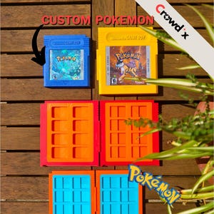 May include: A selection of custom Pokémon Game Boy cartridges and cases. The cartridges are blue and yellow, with game labels. The cases are red, orange, and blue. The text "CUSTOM POKEMON" is visible.