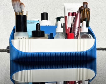 May include: Blue and white organizer with various beauty products, including makeup brushes, lipstick, mascara, and skincare bottles. The organizer has the word "MATH" printed on the front.