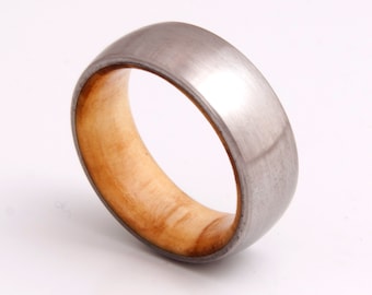May include: A silver and wood ring with a brushed finish. The ring is made of two materials, with a silver band and a wood inlay.