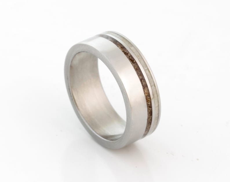 May include: A silver ring with two thin brown lines inlaid into the band.