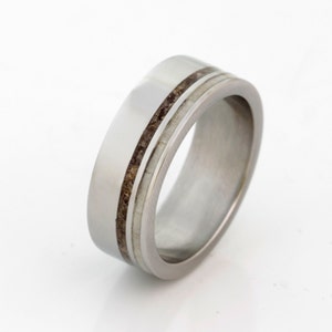 May include: A silver wedding band with two thin brown lines inlaid into the metal.