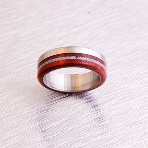 May include: A stainless steel ring with a band of dark red wood and two thin silver lines.