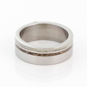 May include: A silver ring with a thin band of brown and white inlay.