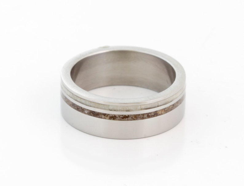 May include: A silver ring with a thin band of brown and white inlay.