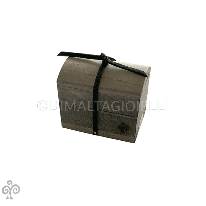 May include: A small wooden chest with a black leather strap tied around it. The chest is closed and has a slightly rounded top.