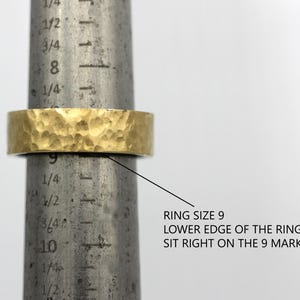 May include: A gold hammered ring sized 9. The lower edge of the ring sits right on the 9 mark of a metal ring sizer.