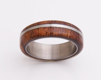 May include: A brown wooden ring with a silver inlay. The ring is made of wood and metal.
