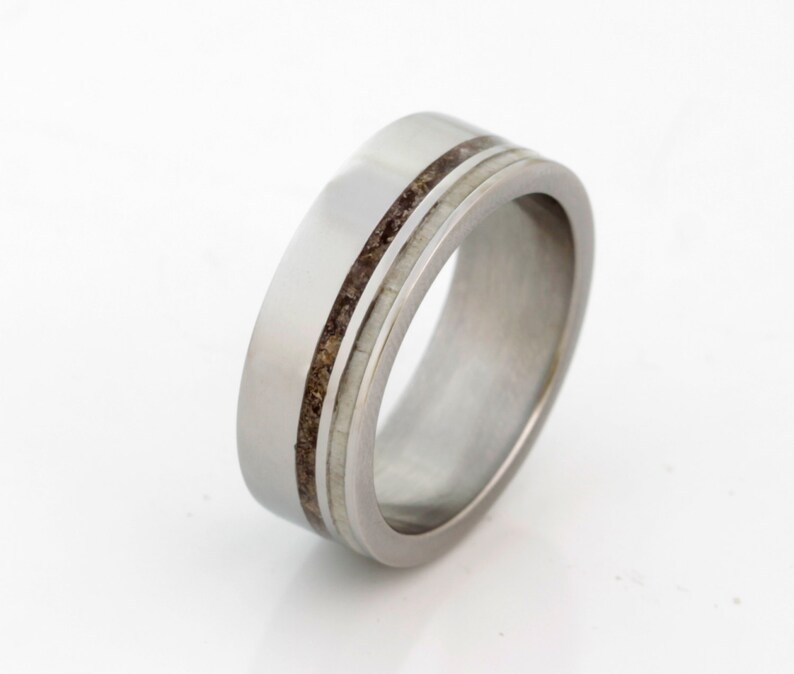 May include: A silver wedding band with two thin brown lines inlaid into the metal.