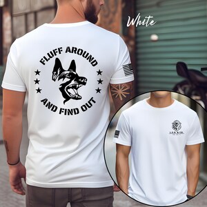 May include: White t-shirt with a black graphic of a dog's head and the text "FLUFF AROUND AND FIND OUT". The shirt also features a small American flag on the sleeve and a logo on the front.