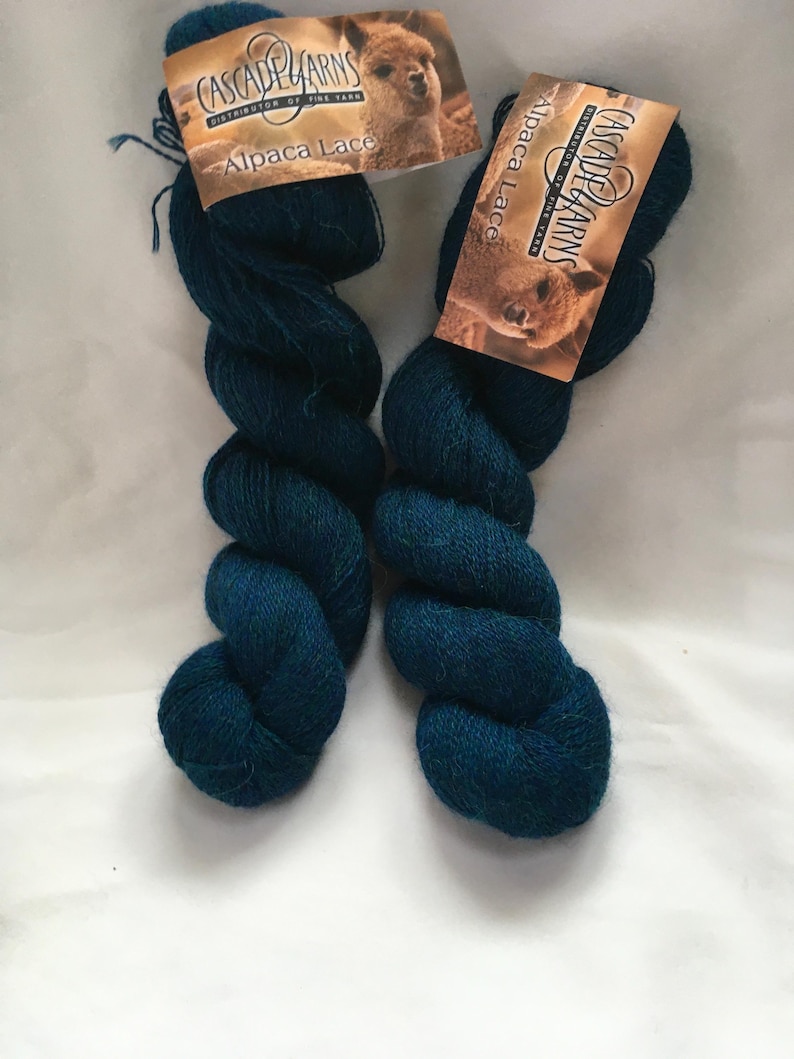 Puede incluir: Dos madejas de hilo Alpaca Lace de Cascade Yarns, color teal. Cada madeja tiene una etiqueta con una imagen de alpaca. El hilo est&aacute; bien enrollado, mostrando su textura y color. Ideal para tejer y hacer ganchillo.