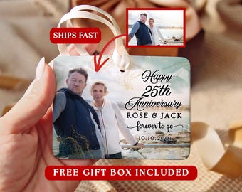 May include: A square ceramic ornament featuring a photograph of a couple, with the text Happy 25th Anniversary, ROSE & JACK, forever to go, and 10.10.2001. The ornament has a white ribbon for hanging and a soft green and gold watercolour background.