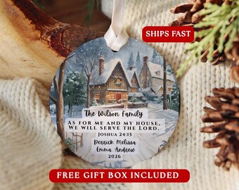 May include: A round ceramic Christmas ornament featuring a snowy winter scene with a house, a white ribbon hanger, and printed text: The Wilson Family, AS FOR ME AND MY HOUSE, WE WILL SERVE THE LORD. JOSHUA 24:15, Derrick, Melissa, Emma, Andrew, 2026.