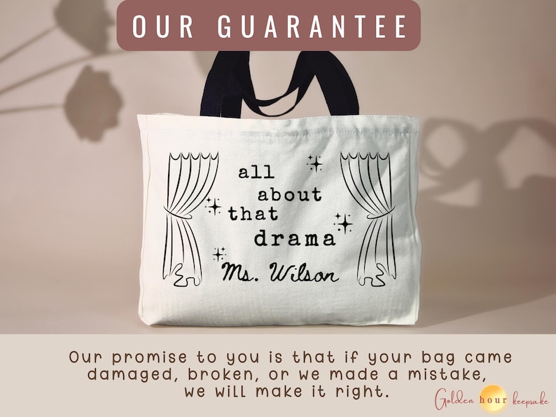 May include: A white canvas tote bag with black handles featuring a black graphic print of stage curtains on both sides. The center text reads all about that drama and Ms. Wilson, accented with small star symbols. The bag has a rectangular shape.