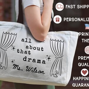 May include: A white canvas tote bag with black text that reads "all about that drama Ms. Wilson" and features curtain illustrations. The bag is held by a person.