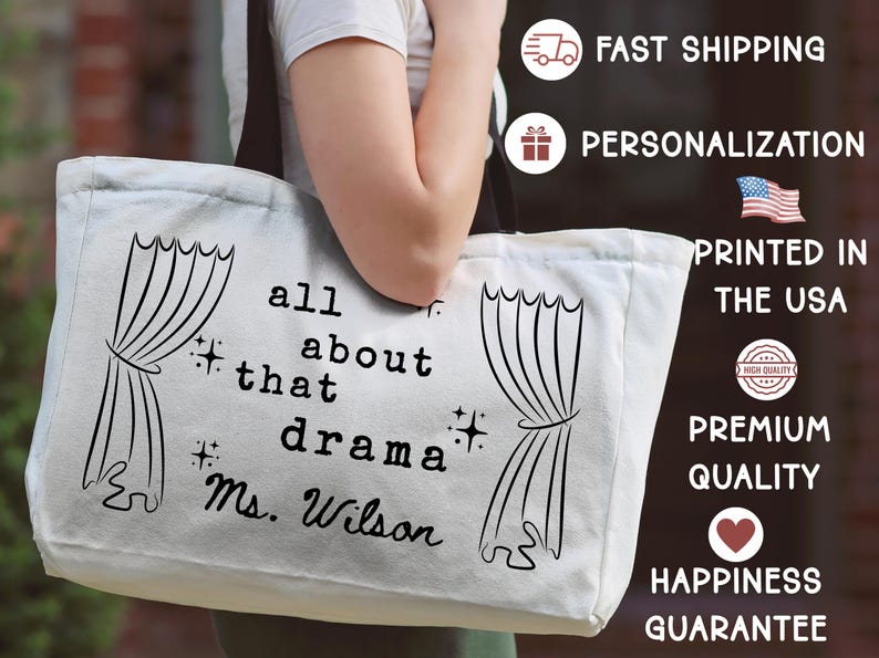 May include: A white canvas tote bag with black text that reads "all about that drama Ms. Wilson" and features curtain illustrations. The bag is held by a person.