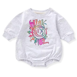 Könnte beinhalten: Ein hellgrauer Baby-Strampler mit langen Ärmeln. Auf der Vorderseite befindet sich ein farbenfrohes Grafikdesign mit den Worten "blink 182" und einem Smiley. Das Design enthält rosa, orange, grüne und blaue Farben.