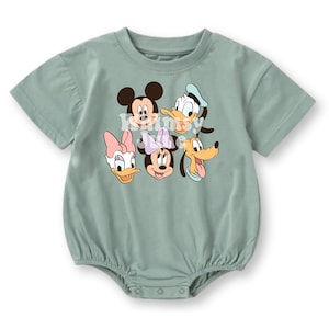 May include: A sage green short-sleeved baby romper featuring a graphic print of Mickey Mouse, Donald Duck, Daisy Duck, Minnie Mouse, and Pluto. The garment has a round neckline and a snap-button closure at the bottom for easy access and changing.