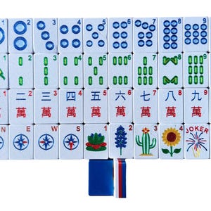 May include: A complete set of white Mahjong tiles with blue, green, and red markings. The tiles feature various symbols, numbers, and Chinese characters. Includes tiles with compass rose, flowers, and the word "Joker".