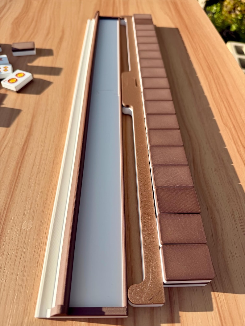 May include: A wooden board game set with a light brown and white frame, a gray playing surface, and brown rectangular game pieces. The set is on a wooden table.