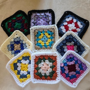 May include: A collection of nine square crochet granny squares arranged in a cluster. Each square features a unique color combination, including shades of red, green, blue, yellow, purple, white, and black, crafted with a central floral pattern.