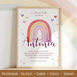 May include: A framed print with a watercolour rainbow in pinks, purples, and yellows, with the name "Antonia" in cursive. The print includes German text, with hearts and dots around the rainbow. The bottom text reads "Multilingual - Deutsch • English • French • Spanish."