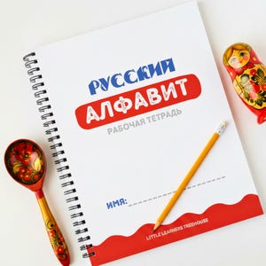 May include: A spiral-bound notebook with the Russian alphabet in blue and red, a yellow pencil, a wooden spoon, and a Matryoshka doll. The notebook has the text "Little Learners Treehouse" at the bottom.