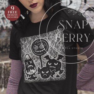 May include: Black t-shirt with a white graphic of cartoon characters, including a lollipop, mushroom, and bat. The shirt has the text "SNAP BERRY DESIGN STUDIO" and "9 FREE DESIGNS INCLUDED". A striped long-sleeve shirt is worn underneath.