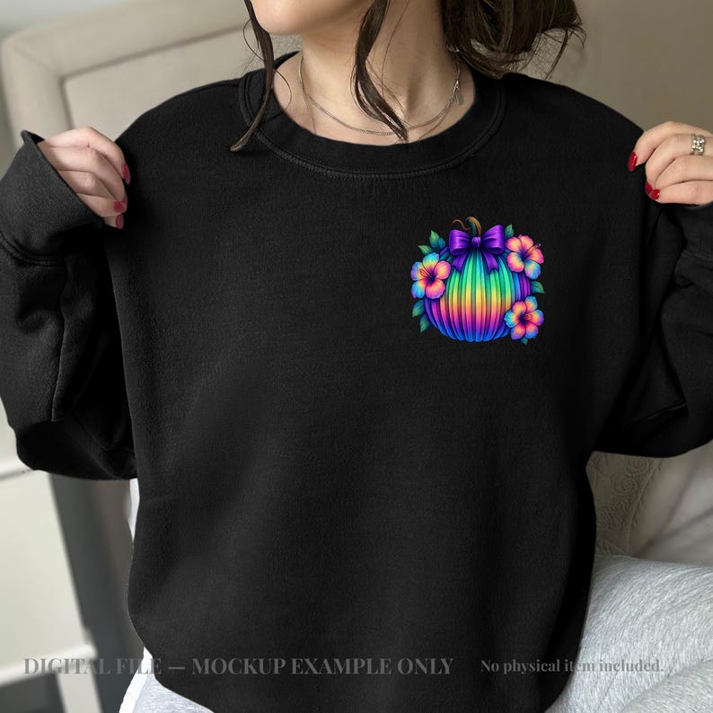 May include: A black crewneck sweatshirt featuring a small graphic on the upper left chest. The graphic depicts a vibrant, rainbow-colored pumpkin adorned with a purple bow and surrounded by colorful tropical hibiscus flowers in shades of pink and blue.