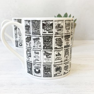 May include: A white ceramic mug with a black and white design of various snack food packaging. The mug has a handle and is printed with the names of popular British snack brands, including McCoy's, Walkers, and Skips.