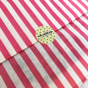 May include: A pink and white striped paper bag with a round sticker that says "marla mitchell design" and "www.marlamitchelldesign.com".
