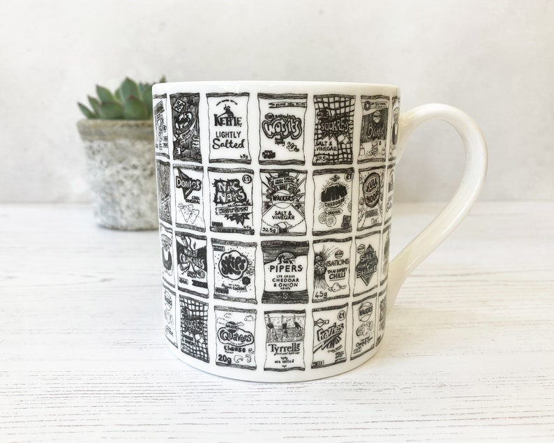 May include: White ceramic mug with a black and white design of various chip bag logos. The logos include brands like Walkers, McCoy's, and Pringles.