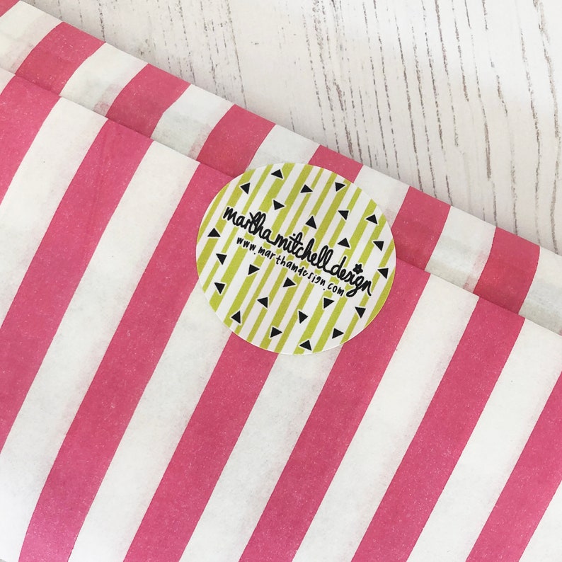 Może przedstawiać: Biały i r&oacute;żowy papier tiulowy w paski z okrągłą naklejką, na kt&oacute;rej widnieje napis "martha mitchell design" i "www.marthamitchelldesign.com" czarnym kolorem na ż&oacute;łtym tle z czarnymi tr&oacute;jkątami.