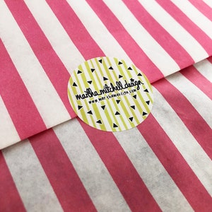May include: A yellow circle sticker with black triangles and the text "martha mitchell design" and "www.marthamitchelldesign.com" on a pink and white striped background.