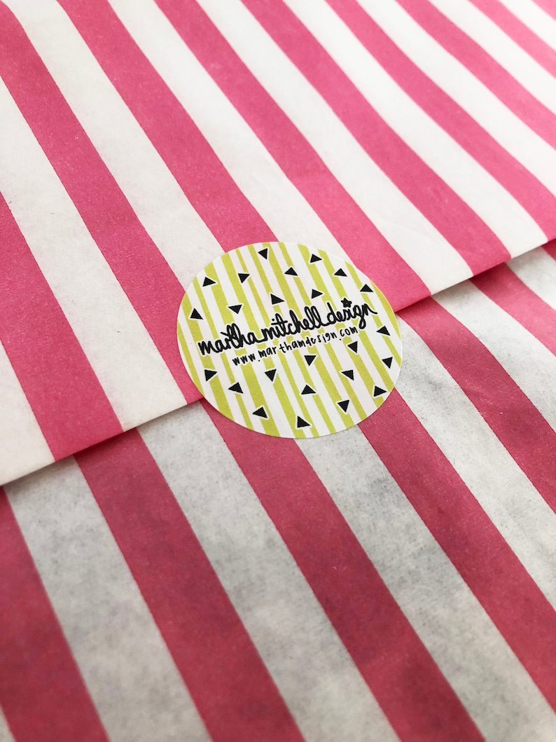 May include: A yellow circle sticker with black triangles and the text "martha mitchell design" and "www.marthamitchelldesign.com" on a pink and white striped background.