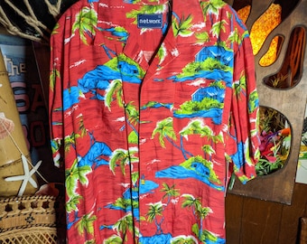 May include: Red short-sleeved button-up shirt with a tropical print of palm trees and islands. The shirt has a white collar and a blue "network" label on the front.