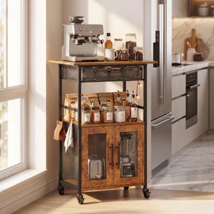 May include: A rolling kitchen cart with a black metal frame and wood-grain finish. It features a top shelf with an espresso machine, a middle shelf with glass jars and bags, and a lower cabinet with mesh doors containing a toaster and blender.