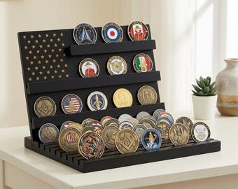 May include: A black wooden display stand featuring a carved American flag pattern with stars on the left side and multiple horizontal shelves holding various circular challenge coins with colorful emblems, insignias, and metallic finishes.