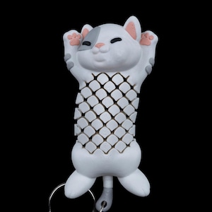 May include: A white cat-shaped keyring with a grey patch over one eye, pink ears, and paw pads. The cat's body has a lattice design. The keyring includes a silver keyring and chain, ideal for attaching to keys or bags.