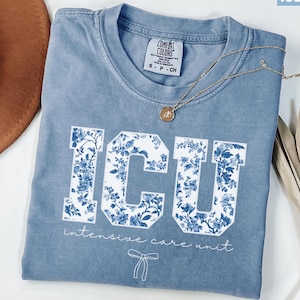 May include: A light blue t-shirt with a white floral print of the letters "ICU" and the text "intensive care unit".