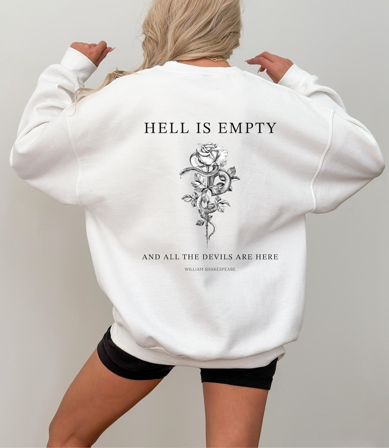 May include: White sweatshirt with the text "HELL IS EMPTY" above a black and white floral and snake design. Below the design, the text reads "AND ALL THE DEVILS ARE HERE" and "WILLIAM SHAKESPEARE". The sweatshirt is a crew neck style.