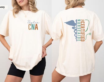May include: Ivory t-shirt with the text "Sophia CNA" on the front and a caduceus with the text "CERTIFIED NURSE AIDE CNA" on the back.