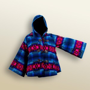 May include: A hooded coat with a vibrant geometric pattern in blue, black, and pink. The coat features toggle closures and a hood. The sleeves are wide and the coat has a unique, eye-catching design.