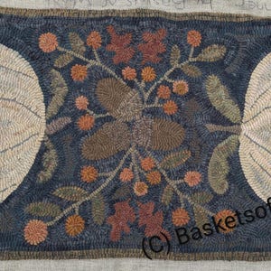 May include: Hand-hooked wool rug with a dark blue background and a central design featuring two large, light-colored pumpkins flanking a floral arrangement. The arrangement includes brown acorns, orange berries, and green leaves. The rug is rectangular.